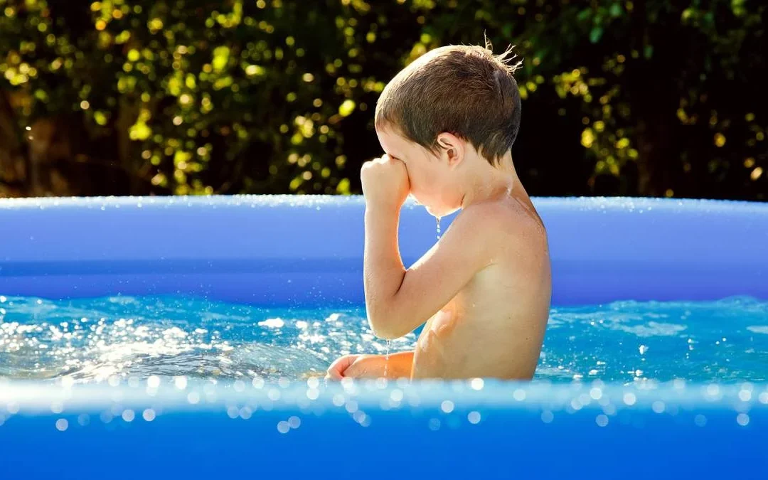 niño frotándose los ojos en la piscina